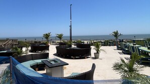 A rooftop terrace with outdoor seating, a view of the ocean, and a clear sky. - Plaza 712 - 2Br/Den/2Ba oceanfront w/indoor,outdoor and kiddie pools. (Ocean City)
