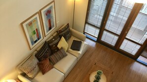 A modern living room with a sofa, pillows, a coffee table, and two framed artworks. - Central Loft Apartment Free Parking (Canberra)