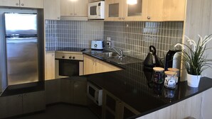 A modern kitchen with stainless steel appliances, a black countertop, and wooden cabinets. - Central Loft Apartment Free Parking (Canberra)