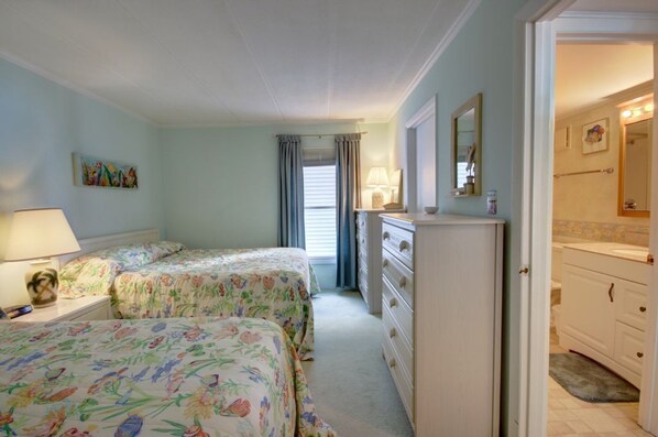 A bedroom with two beds, a dresser, a nightstand, and a painting on the wall.