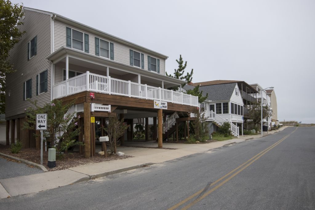 A two-story building with a covered porch and a sign that reads "SANDY."