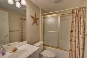A bathroom with a white sink, a toilet, a shower with a gold frame, and a star decoration on the wall.
