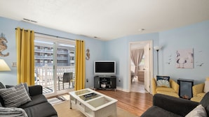 A living room with a sofa, coffee table, TV, and yellow chairs.