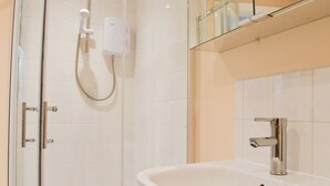 A modern bathroom with a glass shower enclosure, a white sink, and a mirror above the sink.