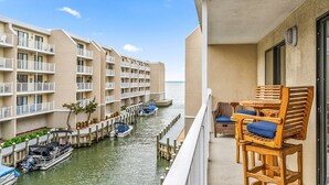 Un hôtel situé en bord de mer, doté de nombreux balcons, d’un espace piscine et de bateaux amarrés le long du rivage.
