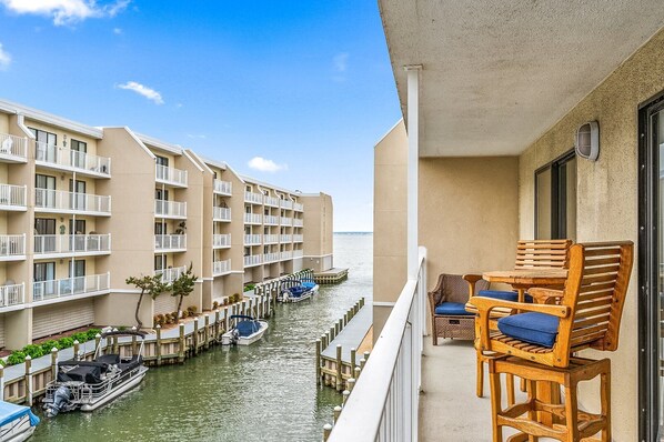 A beachfront hotel with multiple balconies, a pool area, and boats docked along the water.