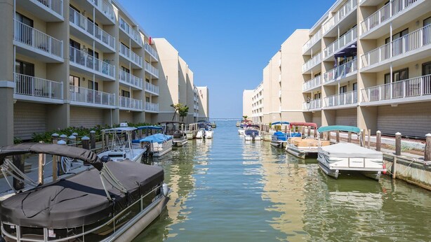Un port de plaisance où des bateaux sont amarrés le long d’un bâtiment doté de nombreux balcons.
