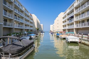 A marina with boats docked alongside a building with multiple balconies.