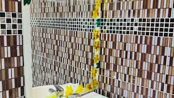 A bathroom with a white sink, a mirror, and a tiled wall with a pattern of brown and beige tiles.
