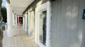 Un corredor cubierto con suelo de piedra estampada, columnas blancas y un edificio con fachada texturizada.