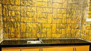 Una cocina con protector de piedra, encimera negra y armarios de madera.