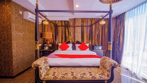 A four-poster bed with red pillows, a bedside table with a lamp, and a large window with sheer curtains. - OYO 562 K Garden Hotel (Sungai Petani)