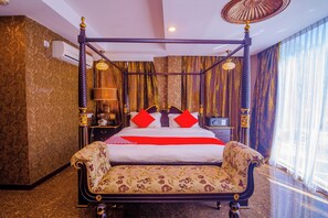A four-poster bed with red pillows, a bedside table with a lamp, and a large window with sheer curtains. - OYO 562 K Garden Hotel (Sungai Petani)