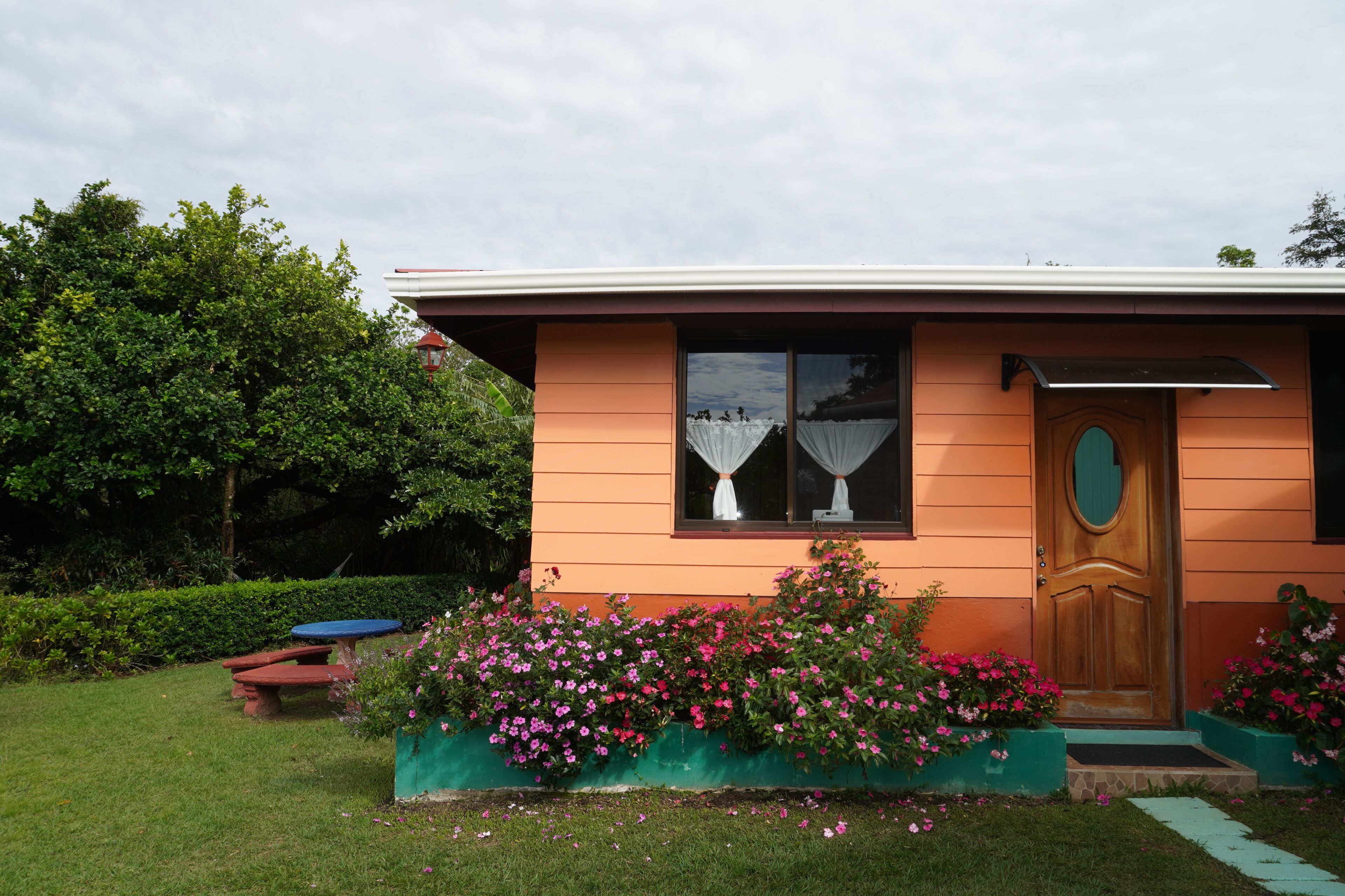 Ein Haus mit Veranda, einer Holztür und einem Fenster mit Vorhängen.