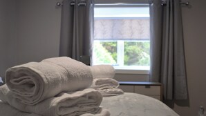 Un letto rifatto con cura, con una coperta a motivi stellati e asciugamani bianchi arrotolati impilati sopra.