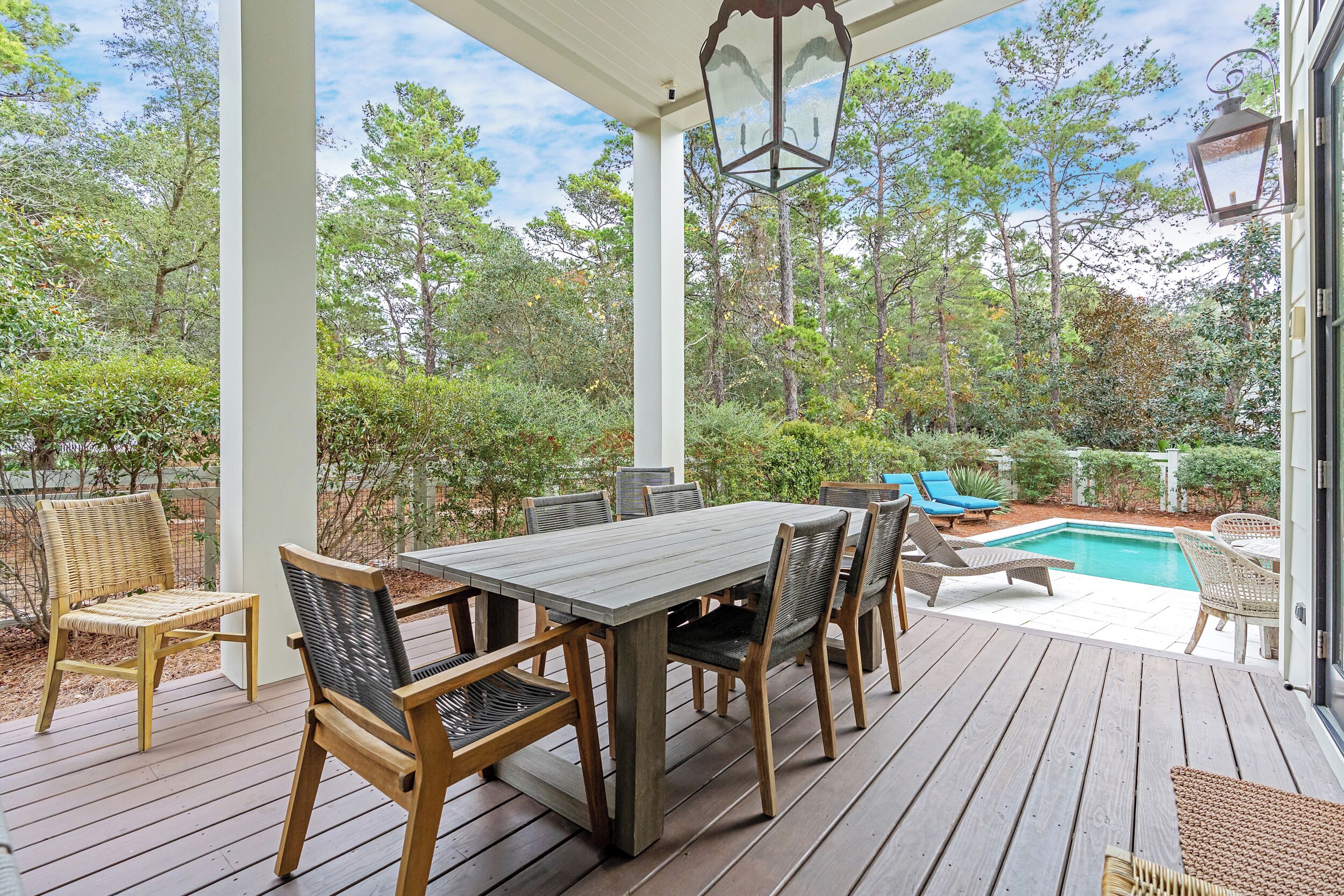 A covered patio with a pool, wooden deck, and outdoor furniture.