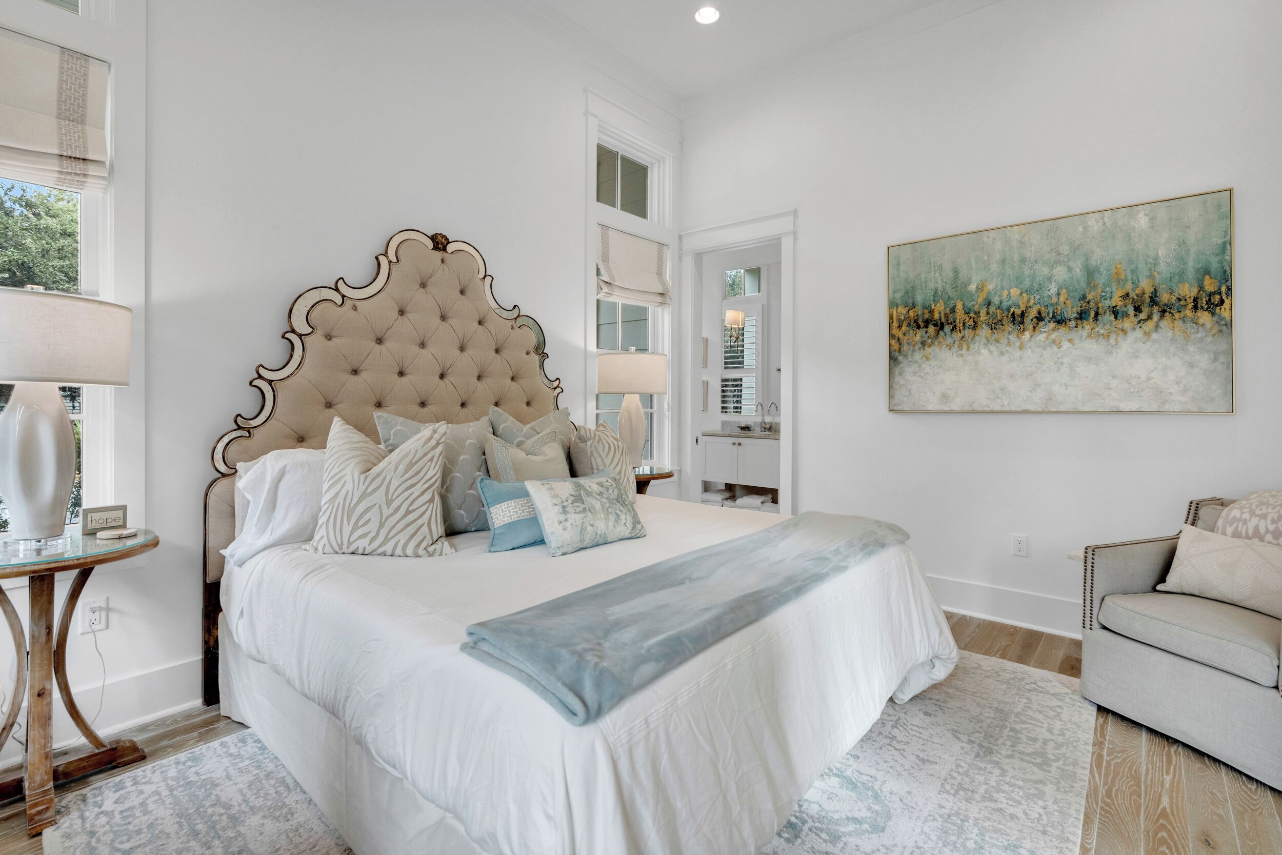 Une chambre avec un grand lit, une table de chevet, une chaise, un tableau et une fenêtre.