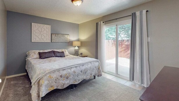 A bedroom with a bed, a nightstand, a lamp, and a window with curtains.