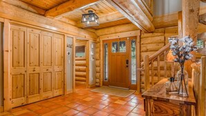 Ein Holzblockhaus-Innenraum mit Holztür, Treppe und Fliesenboden.