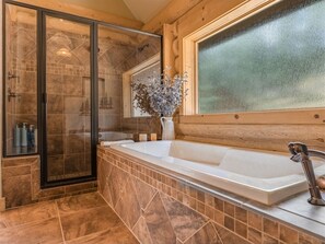 Ein Badezimmer mit Duschkabine aus Glas, einer freistehenden Badewanne und einem Fenster mit Milchglas.