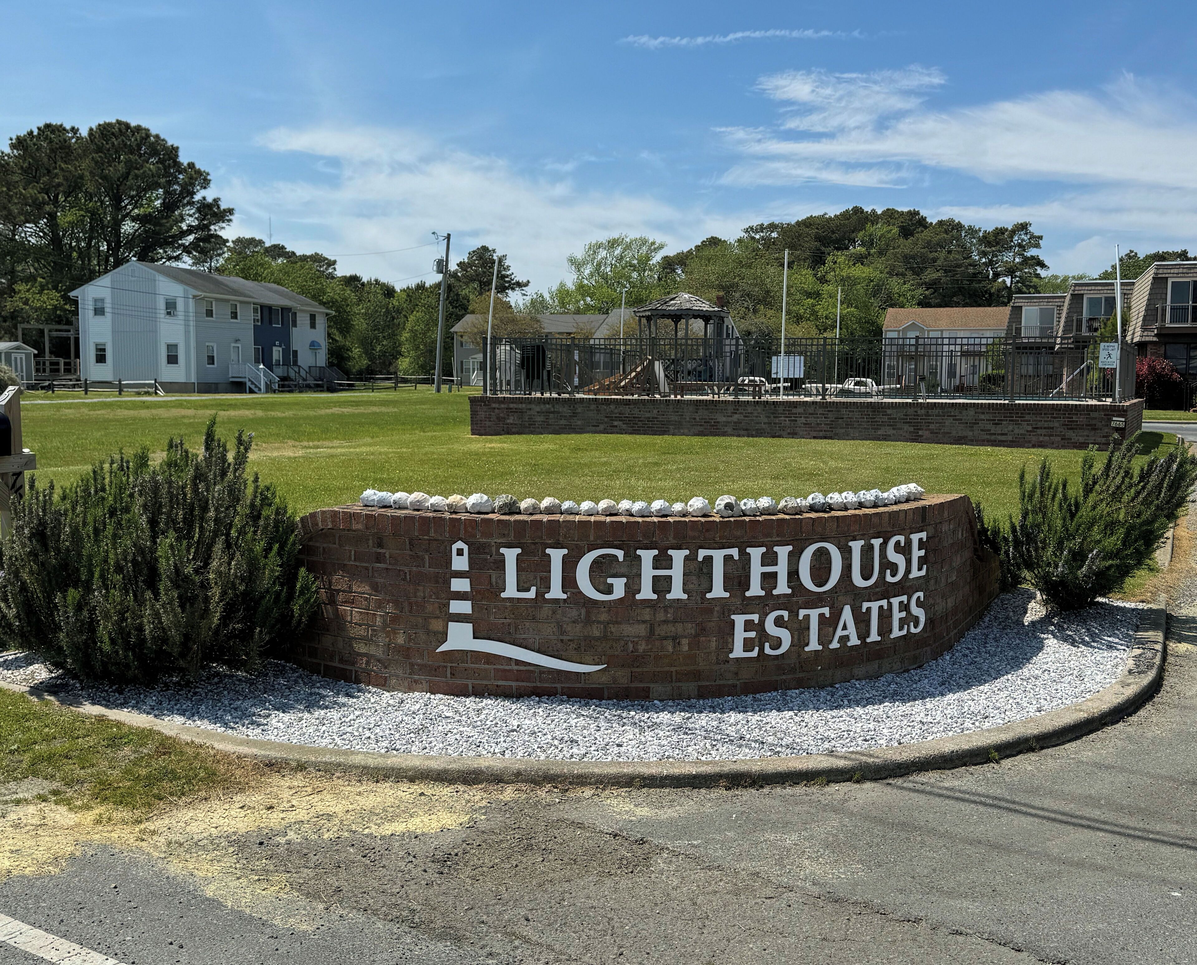 A sign for Lighthouse Estates with a brick wall and a lighthouse graphic.