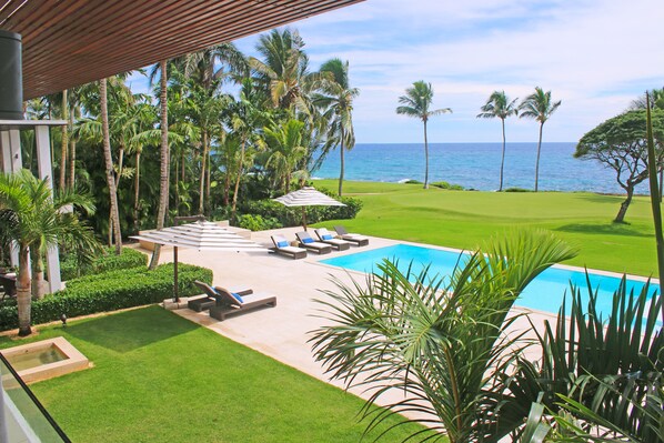 A pool area with lounge chairs and a view of the ocean.