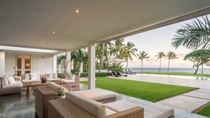 Ein modernes Wohnzimmer mit Meerblick, ausgestattet mit Korbmöbeln und einer Glasveranda.