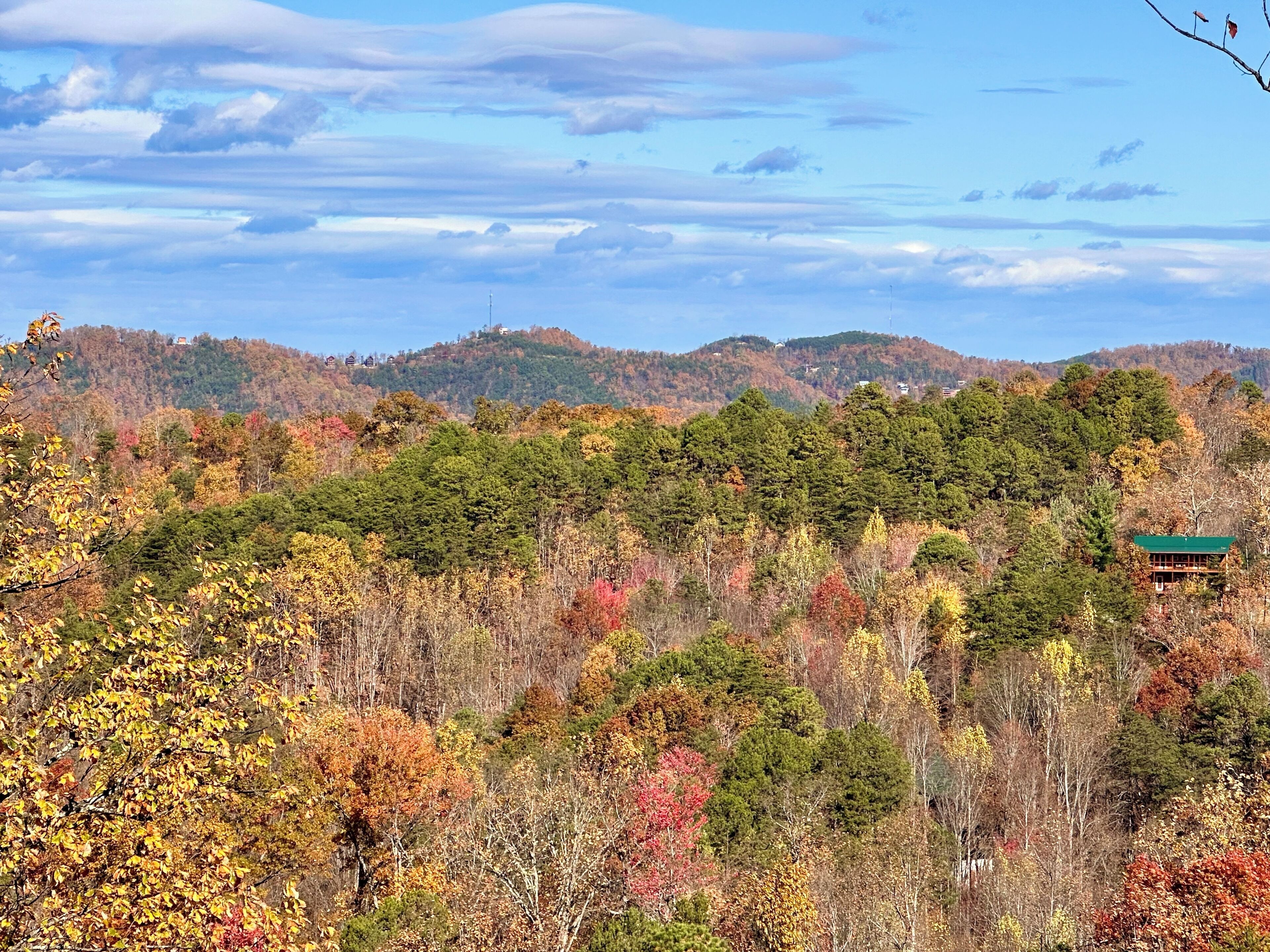 A mountainous landscape with autumn foliage and a cabin.