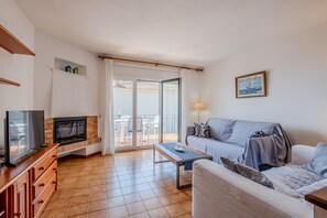 Una sala de estar con televisor, sofá y comedor con sillas y mesa.