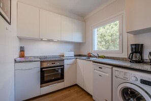 A compact kitchen with a built-in oven, dishwasher, and washing machine. - K-4 Apartment in a quiet area, with swimming pool (Calella de Palafrugell)