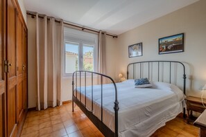 A bedroom with a bed, a nightstand, a lamp, and a window with curtains.