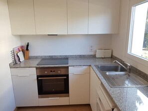 A kitchen with white cabinets, a built-in oven, a toaster, and a window providing natural light.