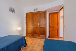 Ein Zimmer mit zwei Betten, einem Kleiderschrank und einer Tür zu einem anderen Raum.
