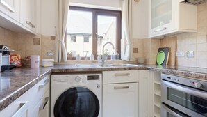 Eine moderne Küche mit Einbauwaschmaschine, Backofen und einem fenster mit Vorhängen.