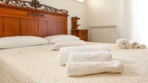 Una cama impecable con toallas blancas enrolladas y un cabecero de madera.