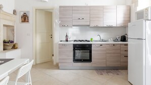 Una cocina moderna con alacenas de madera clara, horno integrado y refrigerador blanco.