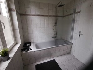A bathroom with a bathtub, shower, and a window.