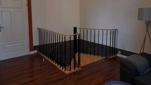 A staircase with a wooden handrail and black balusters, leading to a landing. - Vacation apartment "Villa am Kurpark" - Maisonette (Friedrichroda)