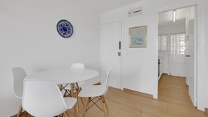 A dining area with a round table and four chairs, a blue decorative plate on the wall, and a door leading to another room.
