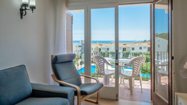 A balcony with a view of the sea and a pool area.