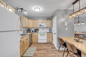 Compact kitchen area with microwave, stove, and dining table.