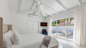 A hotel room with a bed, a TV, a ceiling fan, and a view of a pool and outdoor seating. - Close to Minitas Beach (La Romana)