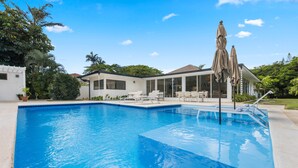 A swimming pool with a clear blue water, surrounded by a patio area with chairs and umbrellas. - Close to Minitas Beach (La Romana)