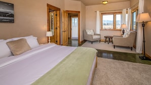 A hotel room with a large bed, a chair, a small table, and a window with curtains. - Home w/river access & stunning views of the mountains in Gallatin Gateway - Le Ciel (Gallatin Gateway)