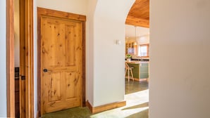 A wooden door leading to a kitchen with a green island and bar stools. - Home w/river access & stunning views of the mountains in Gallatin Gateway - Le Ciel (Gallatin Gateway)
