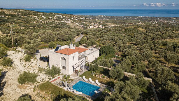 Una villa con piscina, immersa tra ulivi e vista sul mare.
