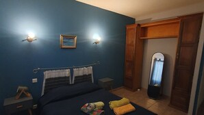 Een slaapkamer met een bed, twee nachtkastjes, een spiegel en een lijst met een afbeelding.