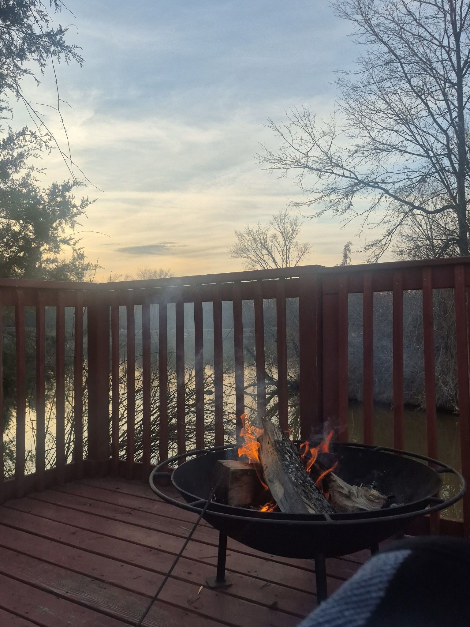 Une terrasse avec un foyer, une rambarde et une vue sur un plan d’eau.