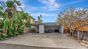 A garage with a covered area, a concrete driveway, and a wooden fence. - ON THE SAND!! Private Beach! OCEAN FRONT HOT TUB!! STR14-0126 (Dana Point)