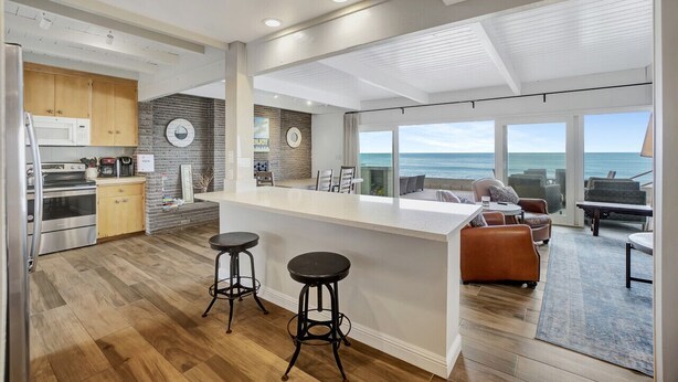 A modern kitchen with a central island, wooden cabinets, and a view of the ocean. - ON THE SAND!! Private Beach! OCEAN FRONT HOT TUB!! STR14-0126 (Dana Point)